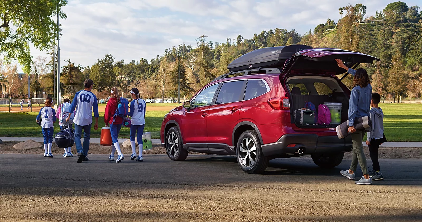 Family relaxing with dog beside Subaru at campsite